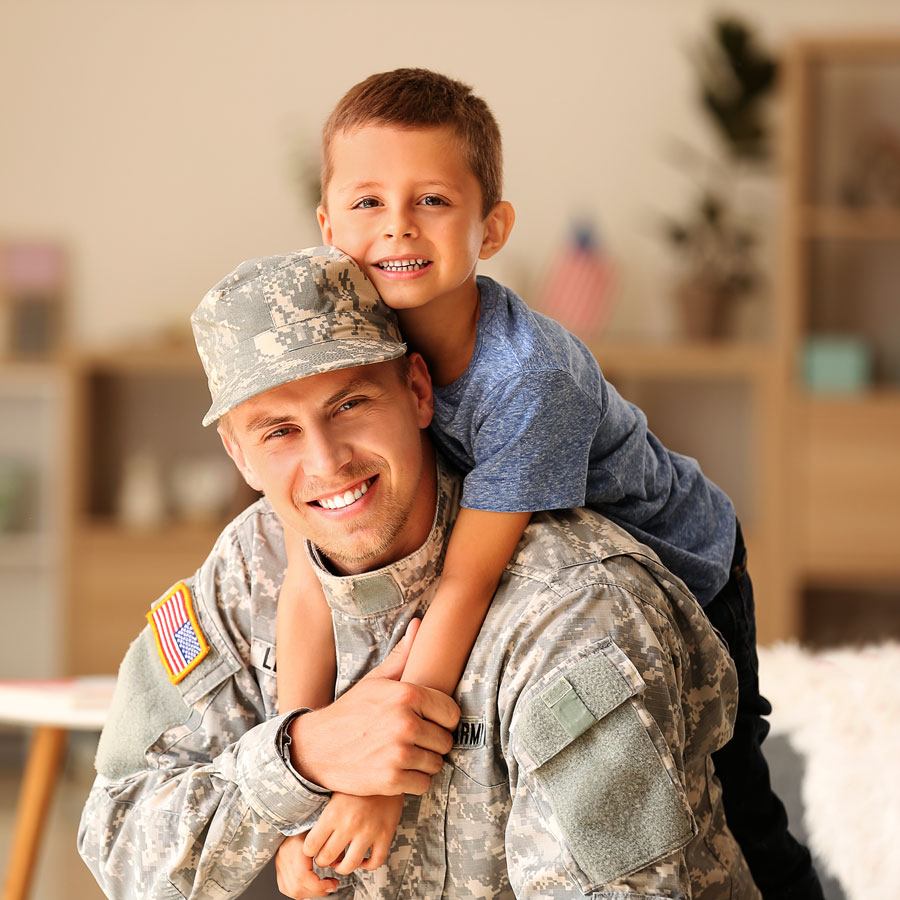 Veteran in uniform with his son hanging on his shoulders