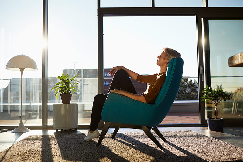 Woman sitting in-armchair in sunlight with closed eyes