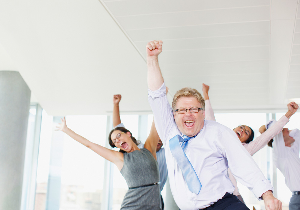 Excited group of coworkers with hands up in the air