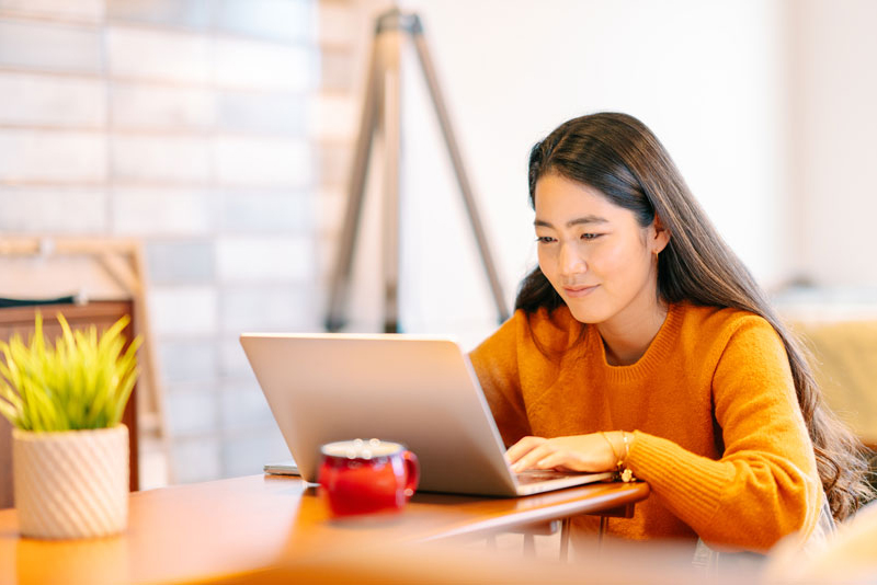 Girl smiling while on her laptop in living room.