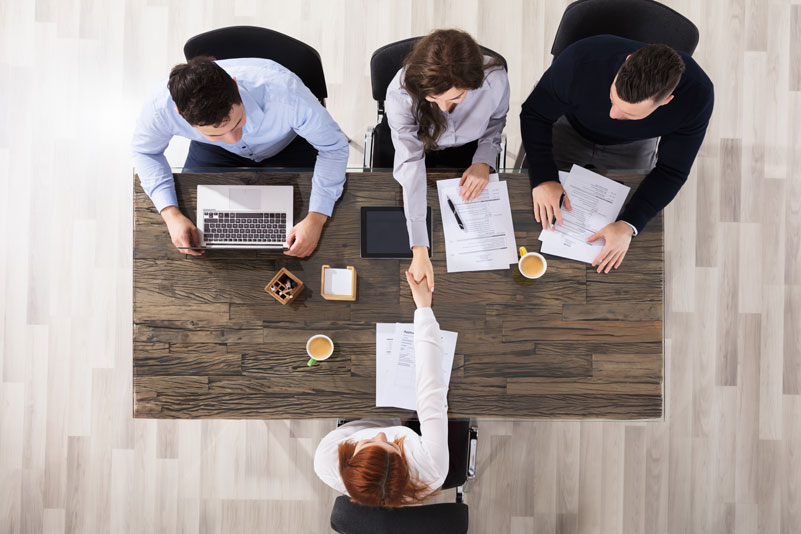 Business people sitting at a desk and shaking hands with client.