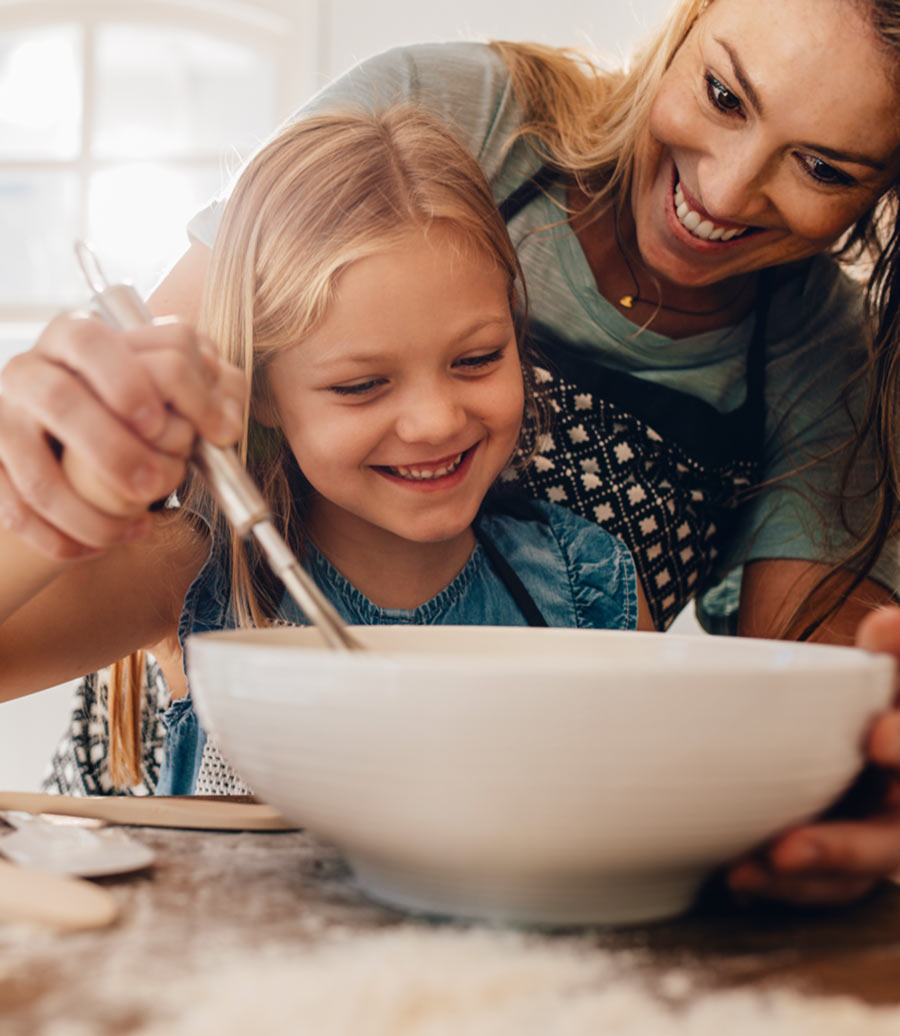 Smiling mom and daughter stirring a bowl