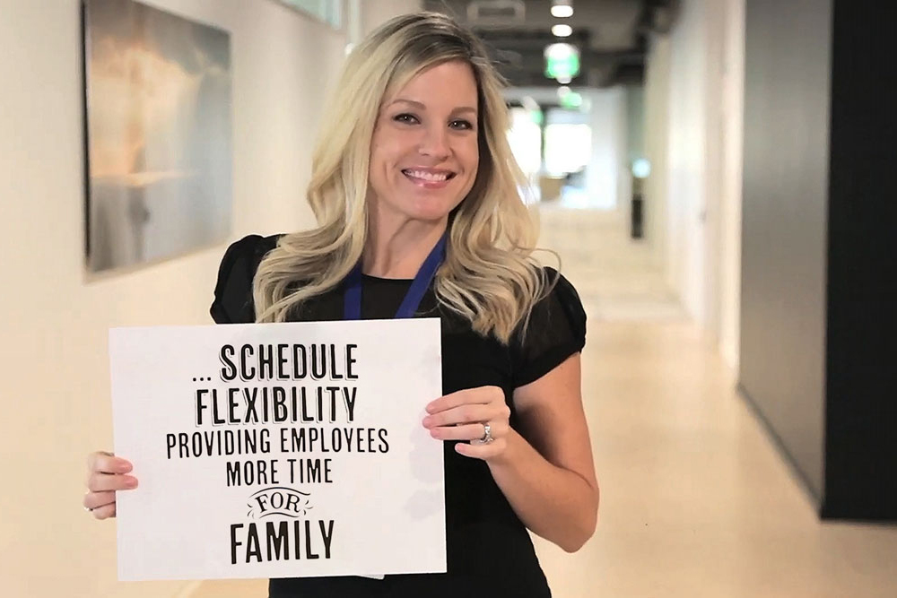 Young woman holding a sign - Schedule Flexibility. Providing employees more time for family.