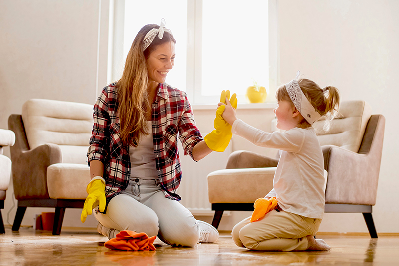 Daughter and mother cleaning home together and having fun.