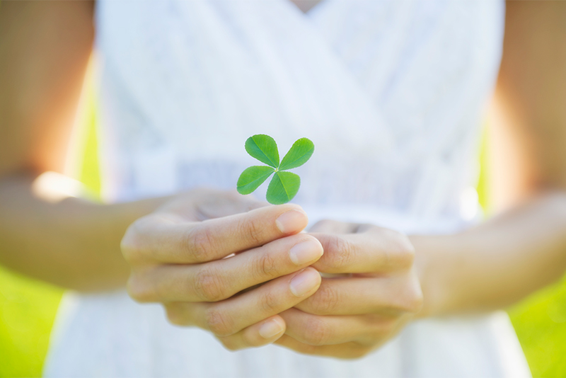 Woman in white dress holding four leaf clover