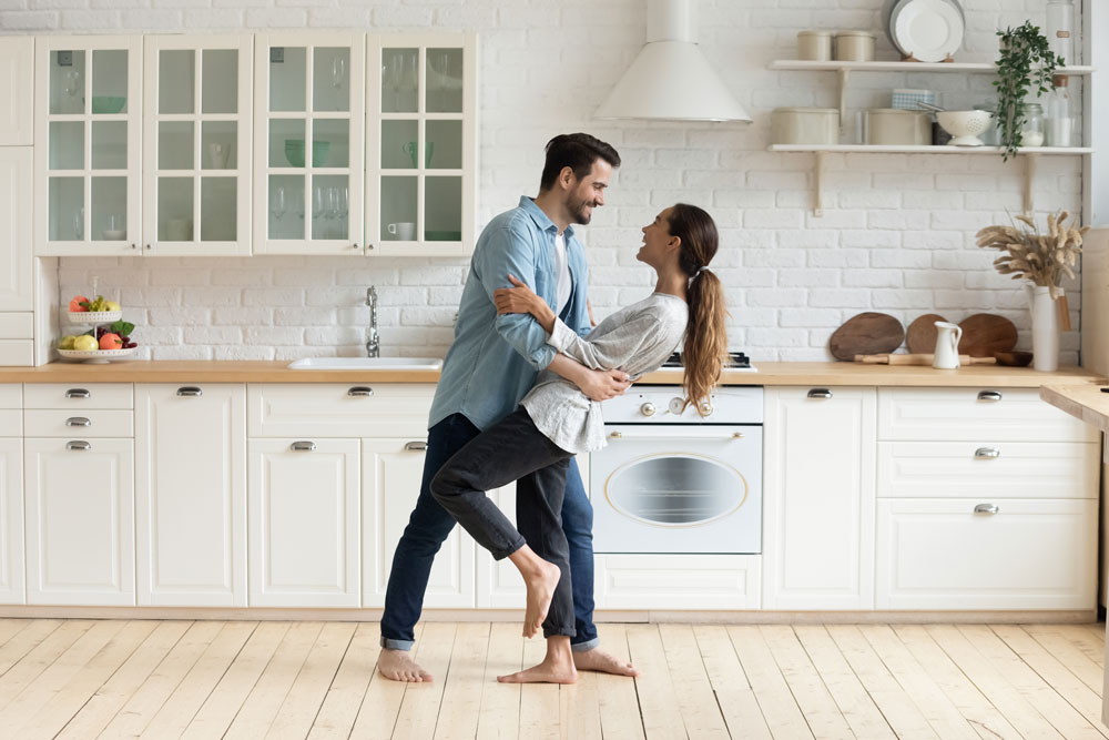 Young man and woman happily dancing in the kitchen.