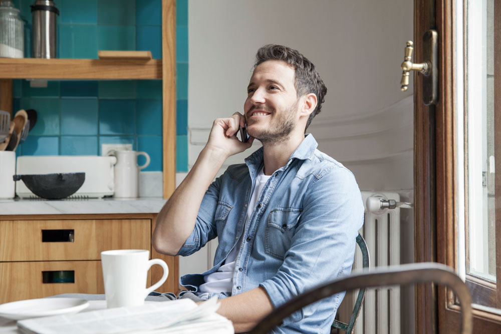 Happy young man on cell phone in the kitchen