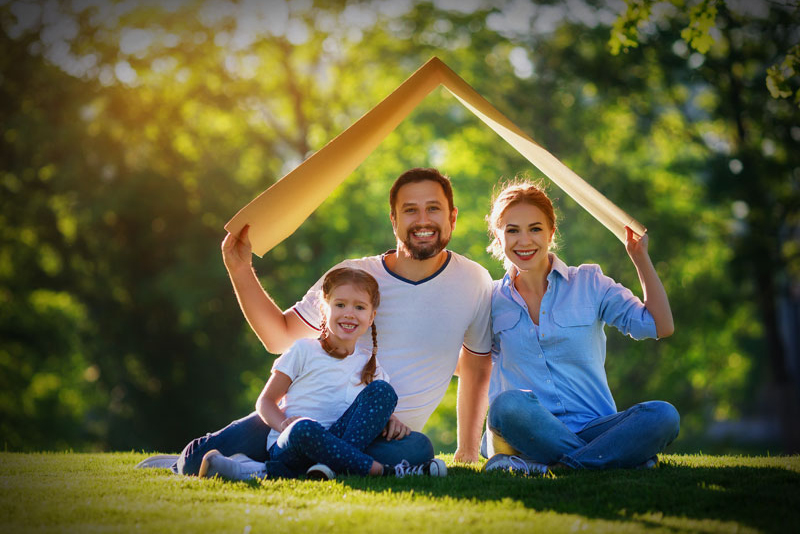 Happy family playing on lawn with cardboard house