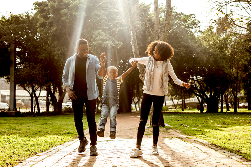 Happy beautiful family of three walking in park