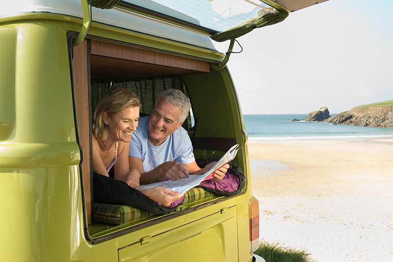 Older couple lying in back of camper van at the beach