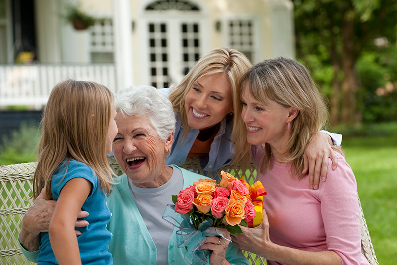 Three generations of woman holding flowers with young girl