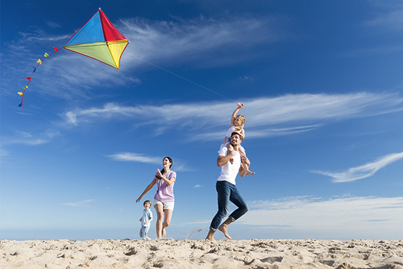 Family Enjoying a Day on the Beach Flying a Kite