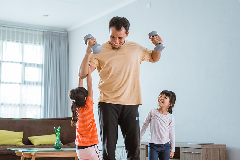 Happy father and daughters exercising in living room