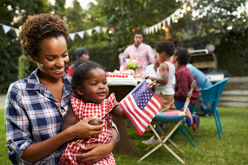 Mother and baby holding flag at labor day garden party