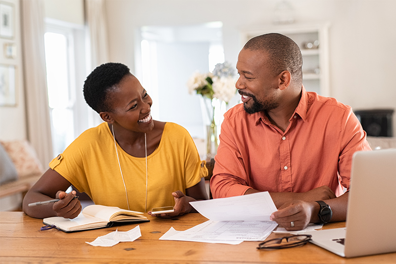 happy couple sitting and managing expenses at home