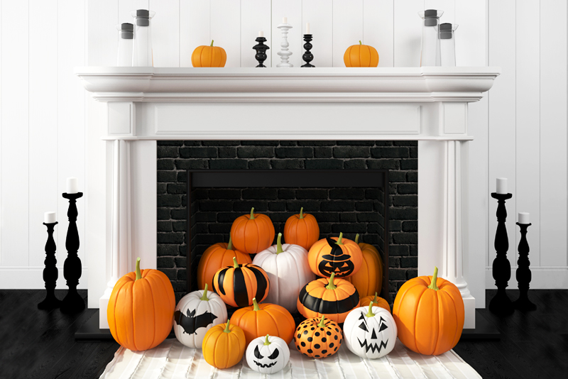 Beautiful white fireplace in the classic style against a white wall and decorated with painted pumpkins