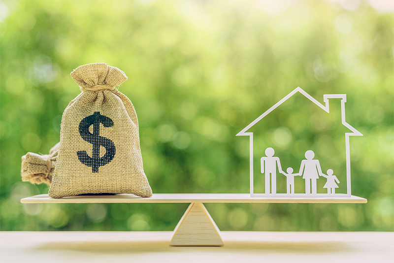 Scale balanced with money bag and family inside a house