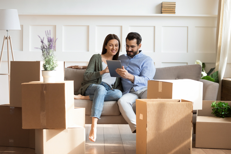 Happy couple sitting on couch among moving boxes