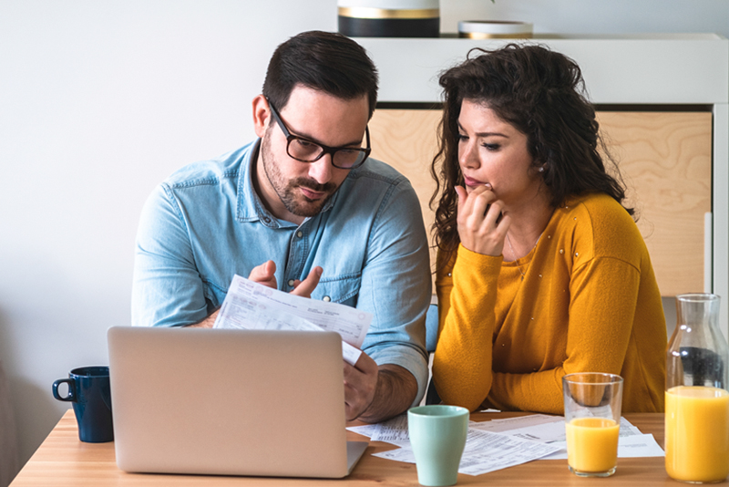 Worried couple looking at bills with laptop