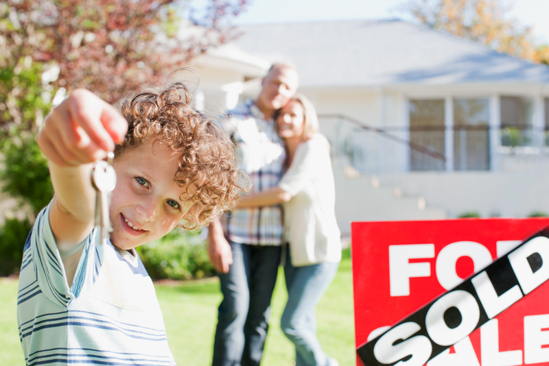 Family in front of sold sign with kid holding house keys