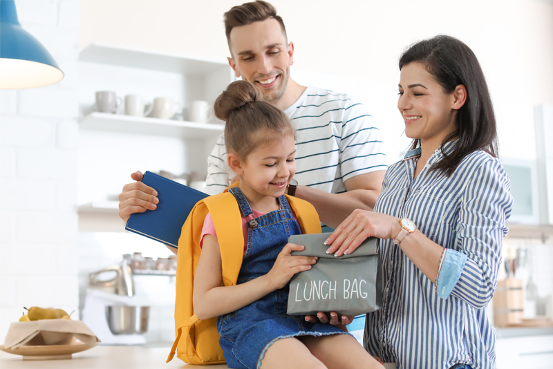 Happy parents getting daughter ready for school