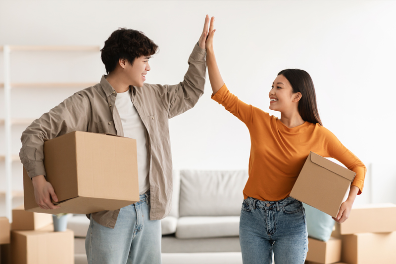 Happy couple holding moving boxes and high-fiving each other