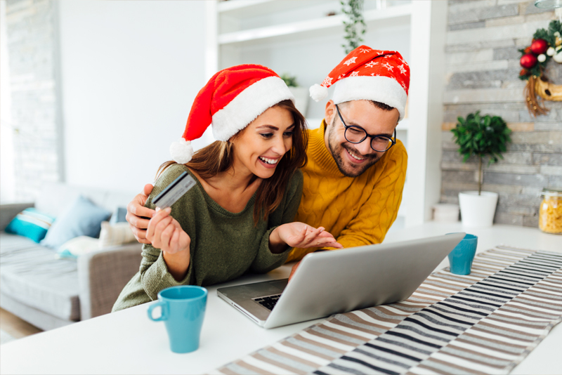 Excited couple in santa hats online shoppipng with credit card