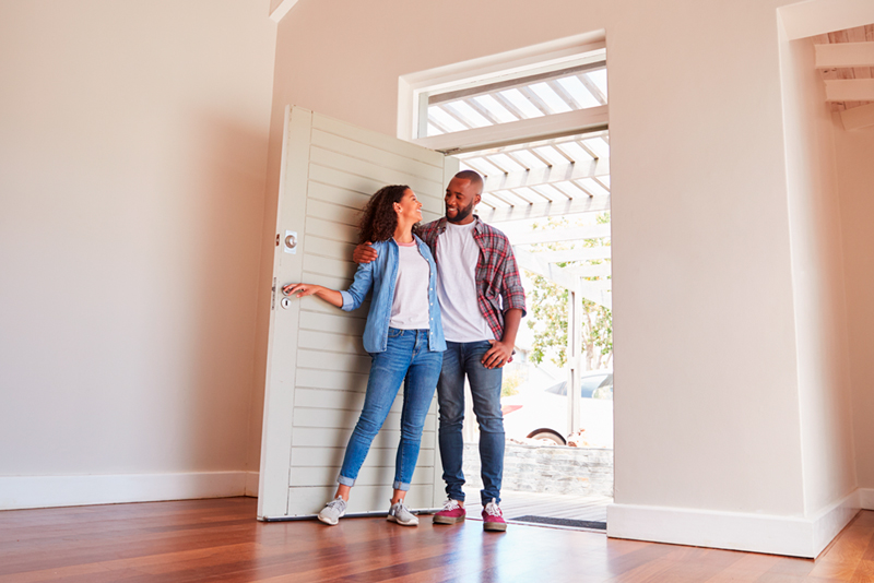 Excited couple walking into new home with no furniture