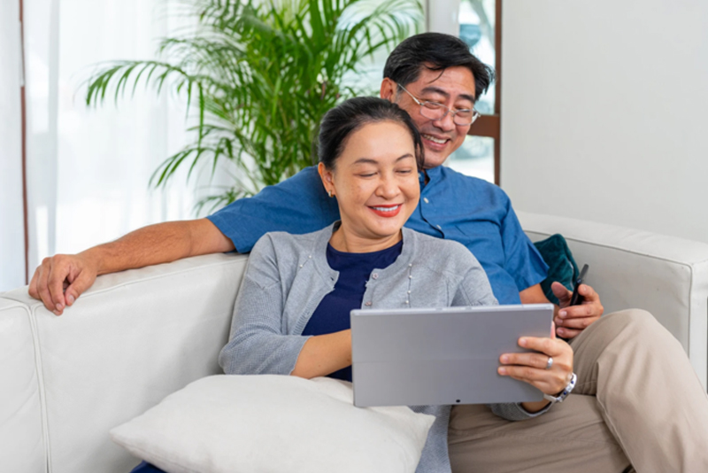 Happy couple sitting on couch with tablet computer