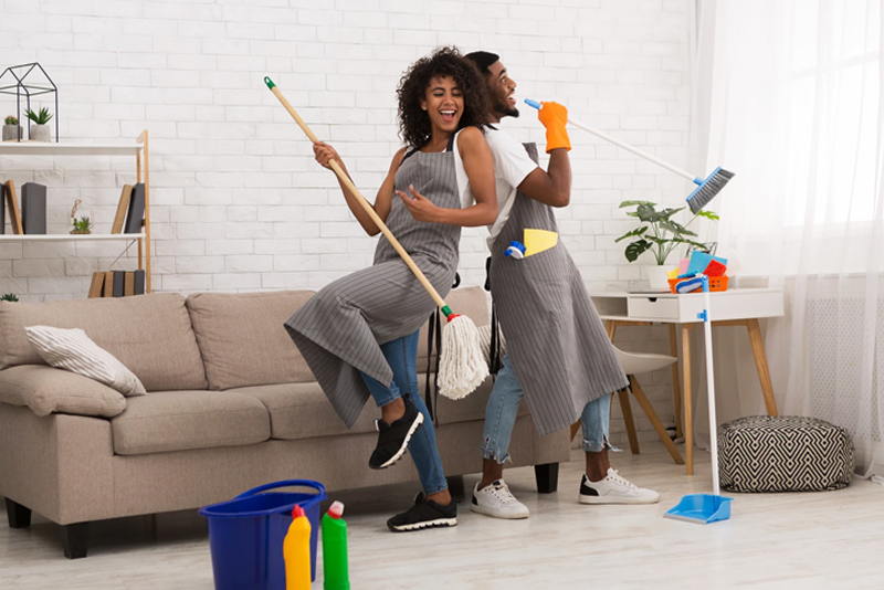 Happy couple dancing while cleaning living room