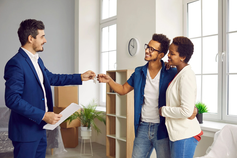 Happy couple receiving house keys from real estate professional