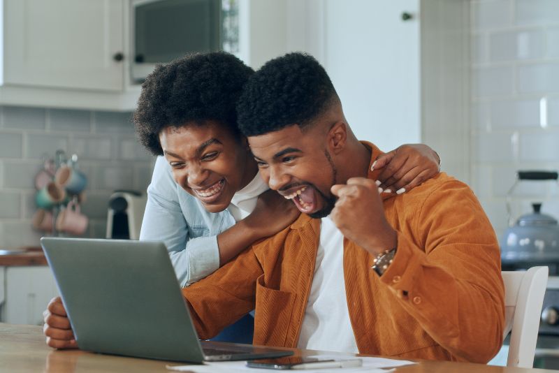 couple looking at laptop excited in the kitchen