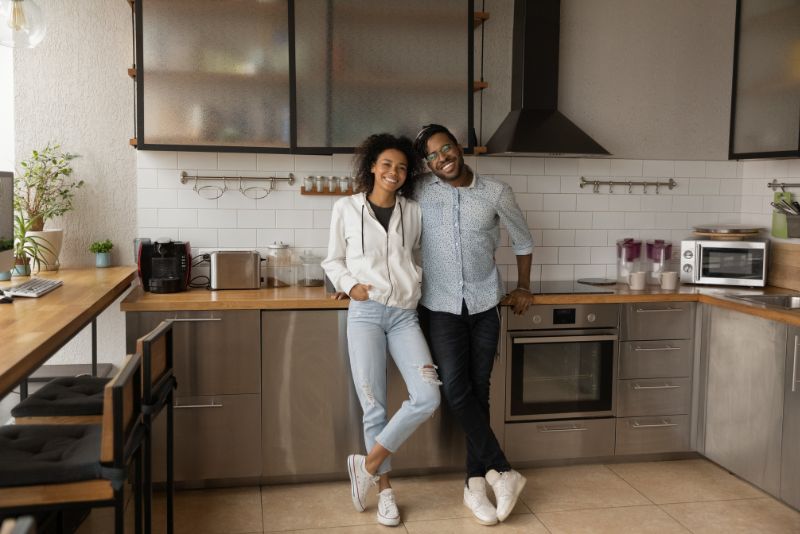 Full length portrait happy couple standing in kitchen